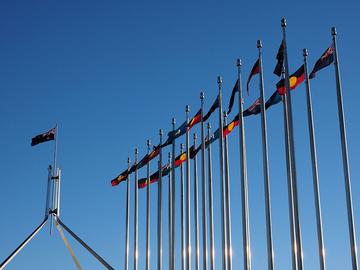 aboriginal torres strait islander and australian flags outside the australian parliament house in july